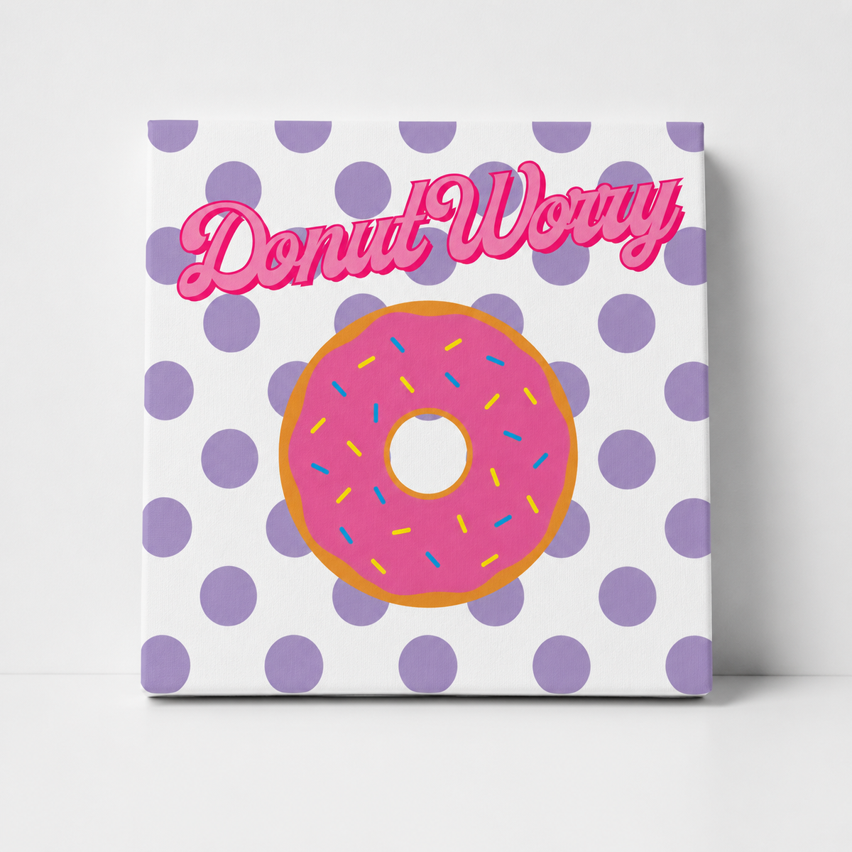 A square canvas print featuring a pink donut with colorful sprinkles on a white background with purple polka dots, and the text 'Donut Worry' in pink script across the top.