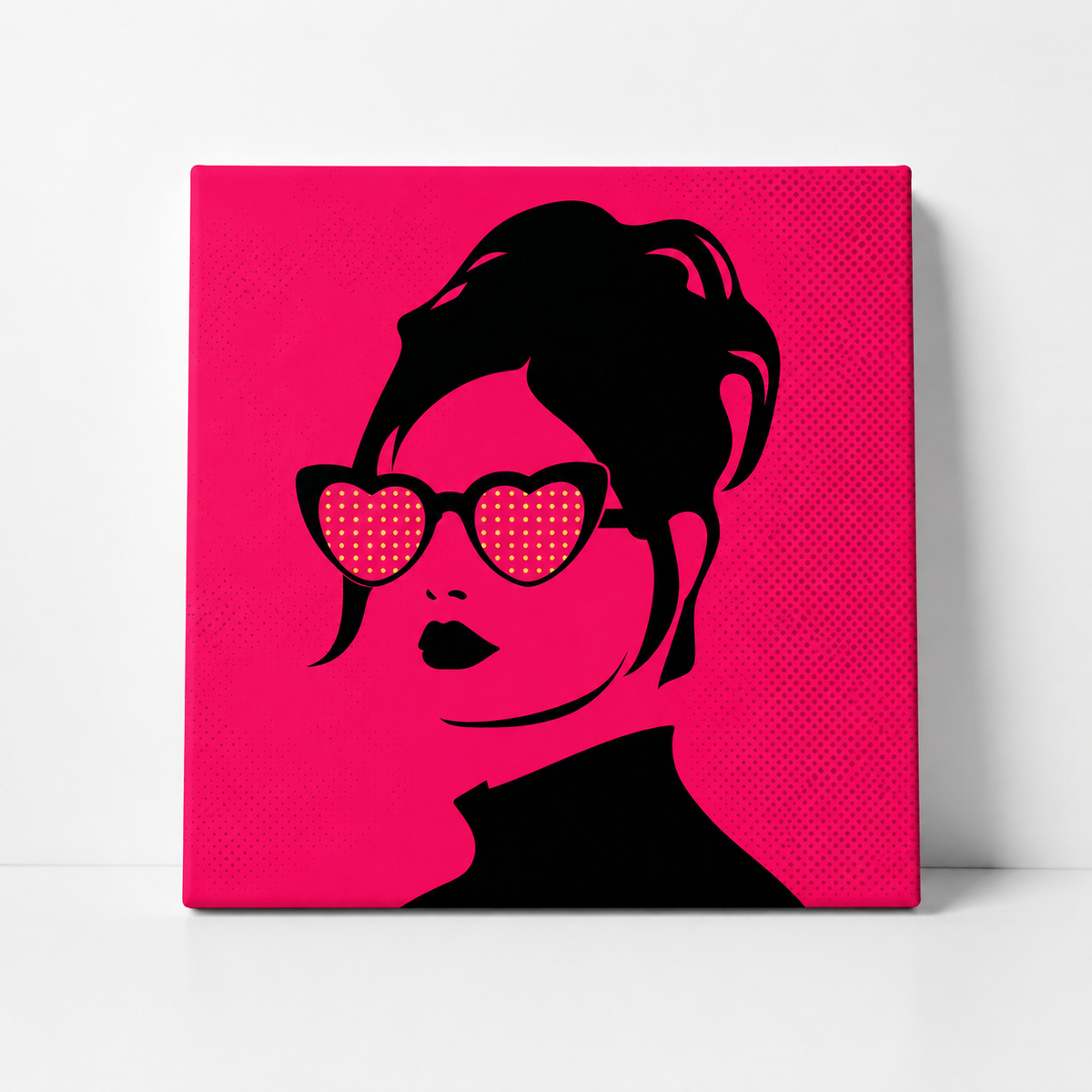 A square canvas wall art print featuring a stylized black silhouette of a woman with heart-shaped sunglasses on a bright hot pink background, shown leaning against a white wall.