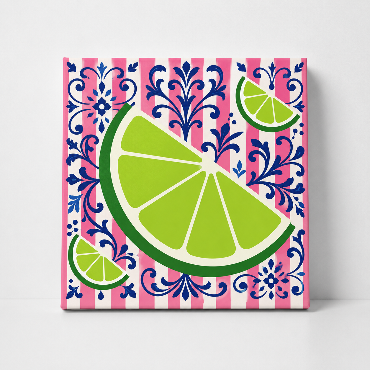 A square decorative tile or coaster featuring a vibrant lime wedge and smaller lime slices over a pink and white striped background with a blue damask pattern, shown standing upright against a light gray wall.
